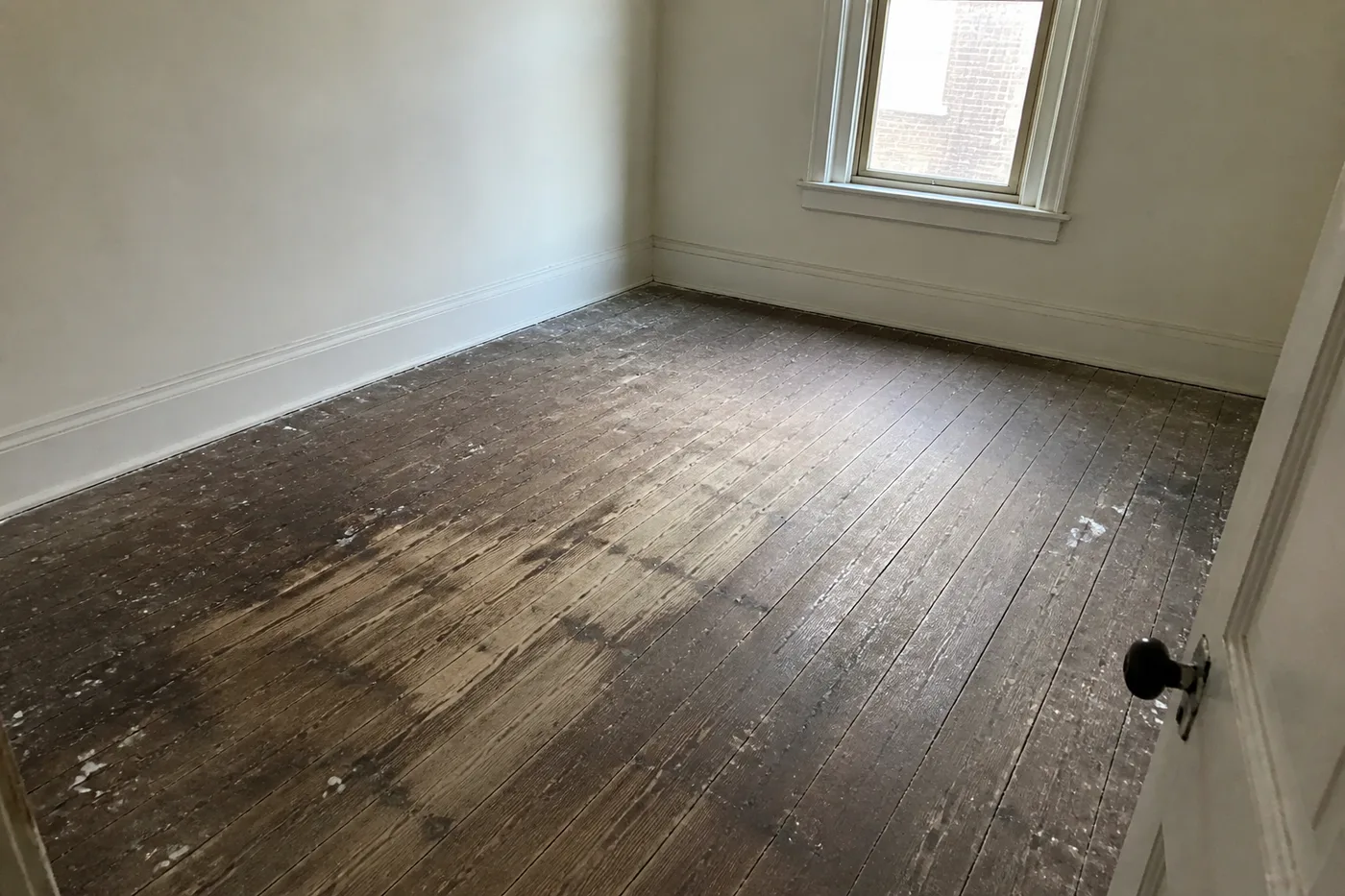Grimy, paint-spattered original wide-plank heart pine floor worn gray in places